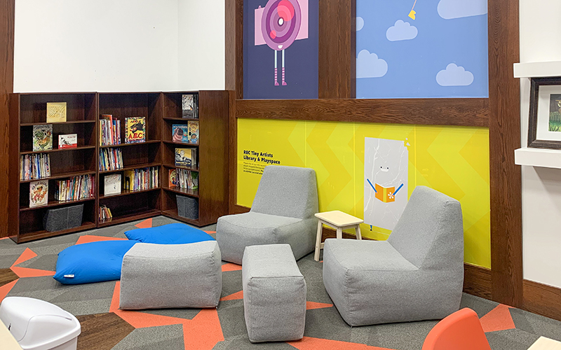 Big comfy gray seats near a bookshelf full of books