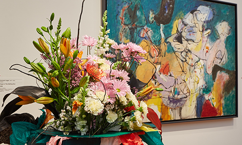 a vase of flowers accompanies a painting