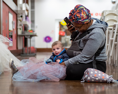 A parent holds their child as they try on a tutu in the REC