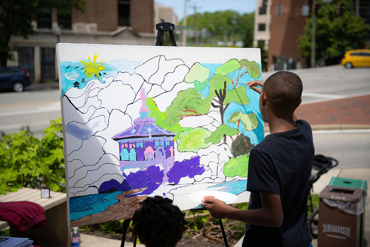 A young Black kid paints outdoors