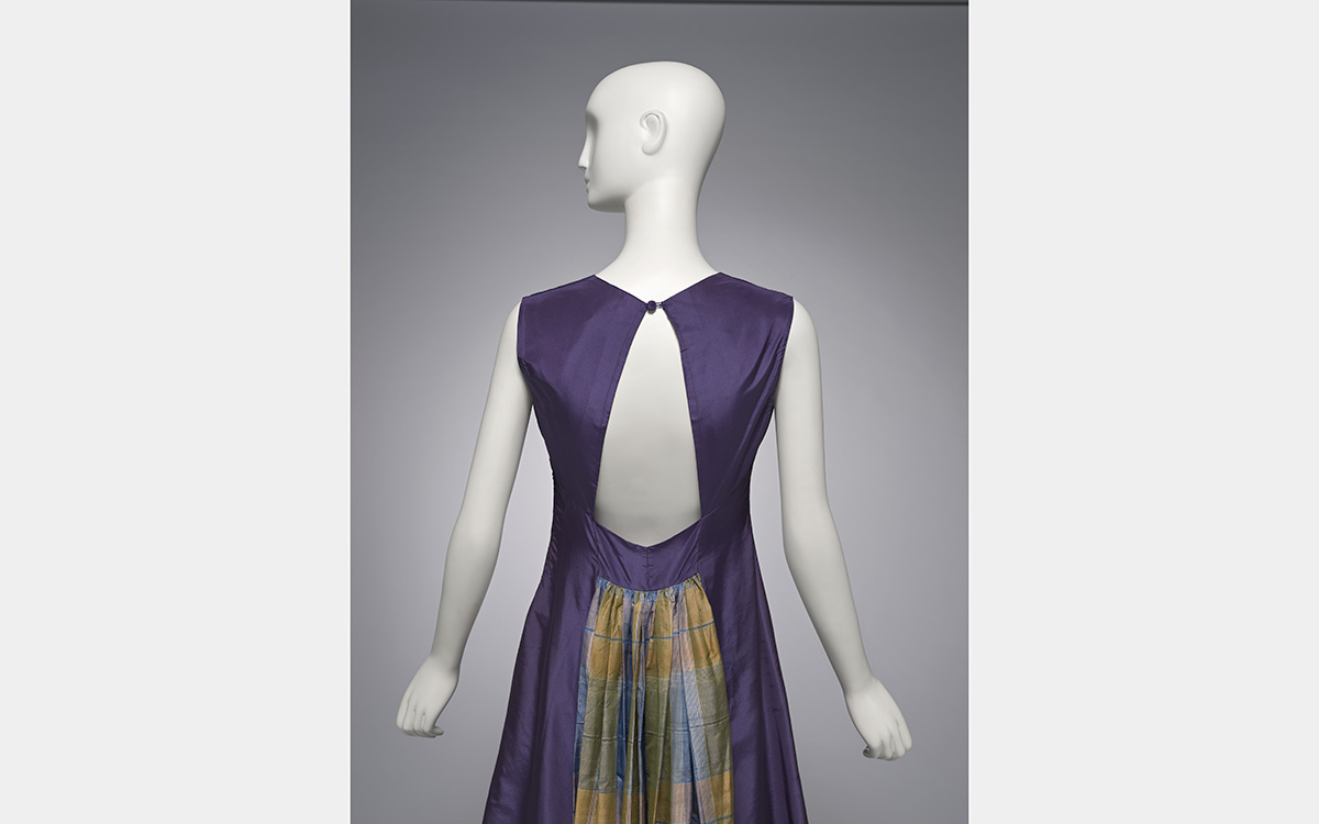 Back view of a white mannequin wearing a dark blue dress with plaid insert below the waist.