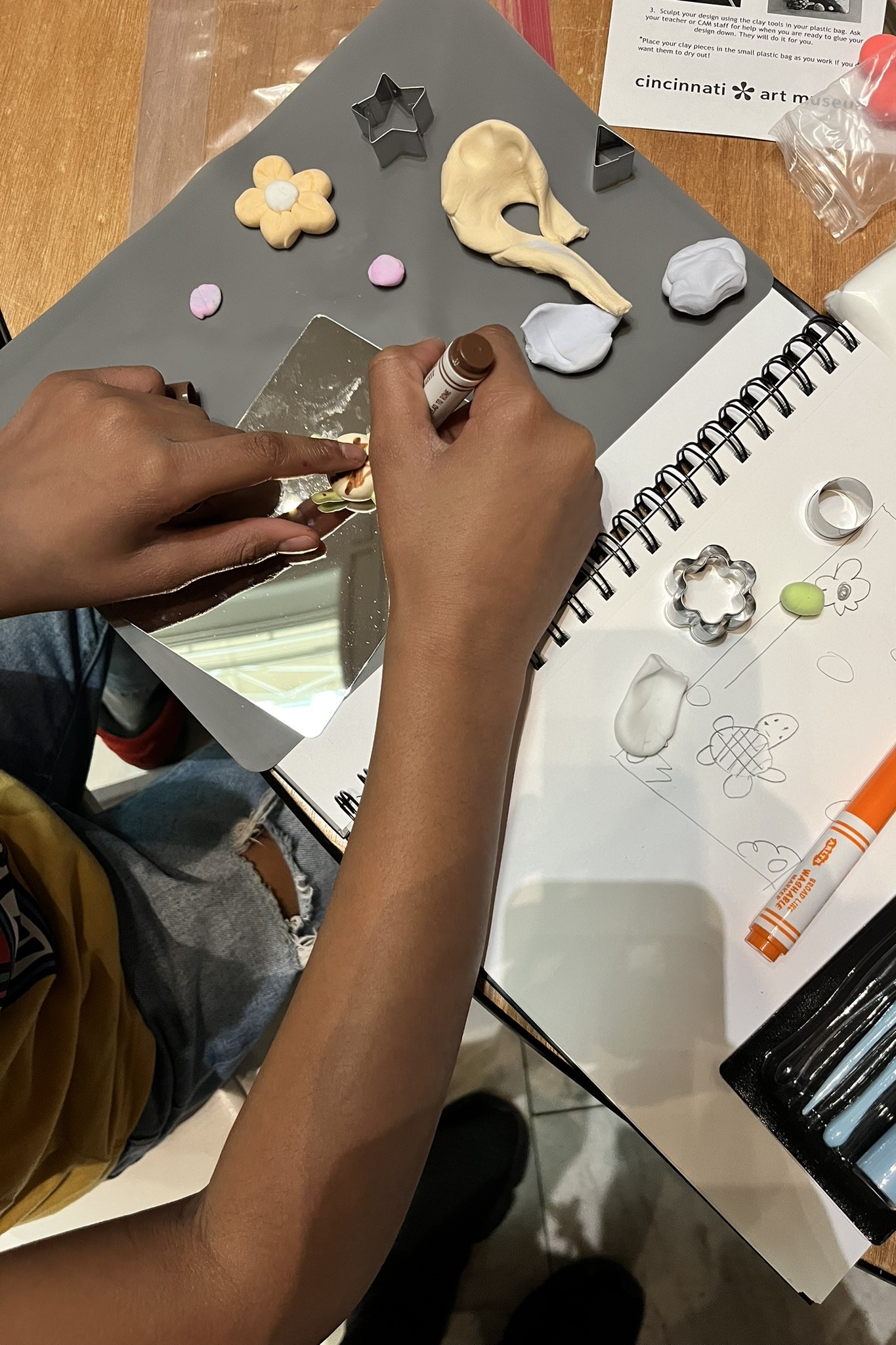 View from above a child's arm and hand making art on a table.