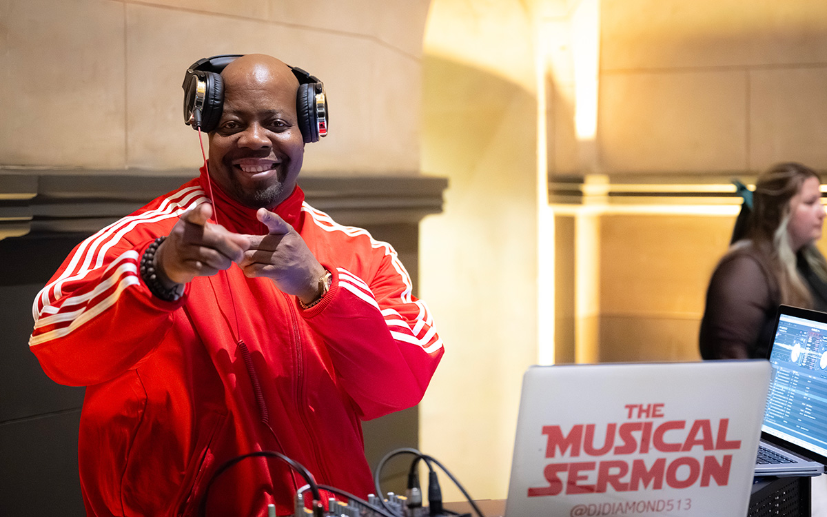 A Black DJ points at the camera and smiles