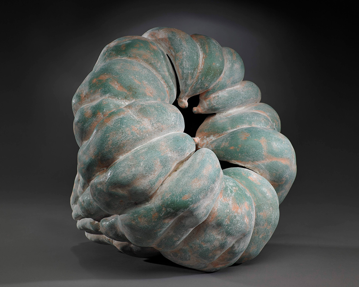 A pumpkin shaped ceramic vessel in shades of green and orange