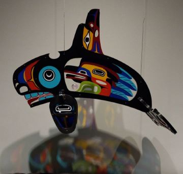 A glass sculpture of an Orca whale with blue, yellow and red decorations