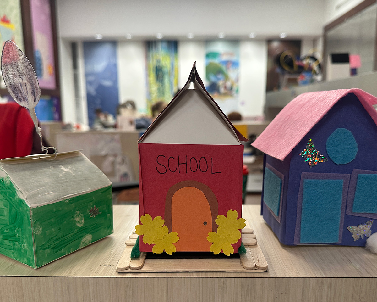 Three toy houses made of paper and assorted colorful materials