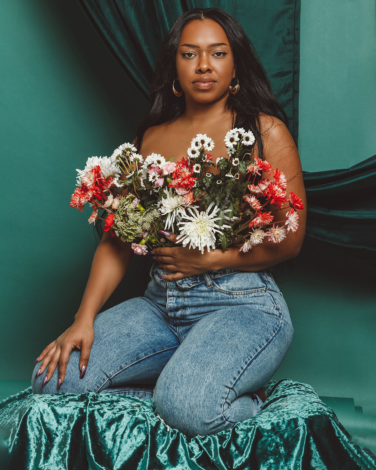 A Black woman with long black hair posing with a bouquet of flowers