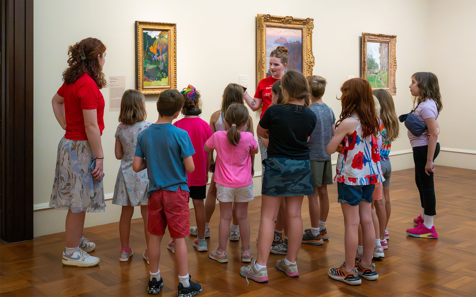 A group of students listen to a chaperon in a gallery