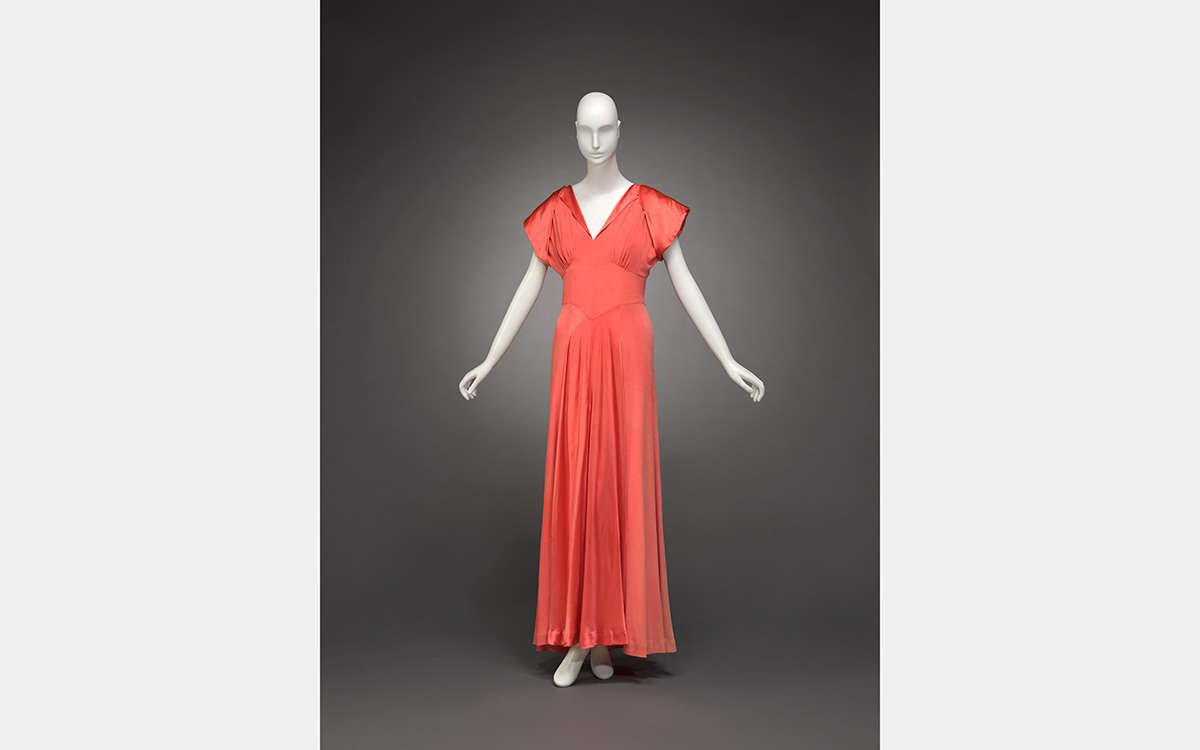 White mannequin wearing a long orange-colored dress