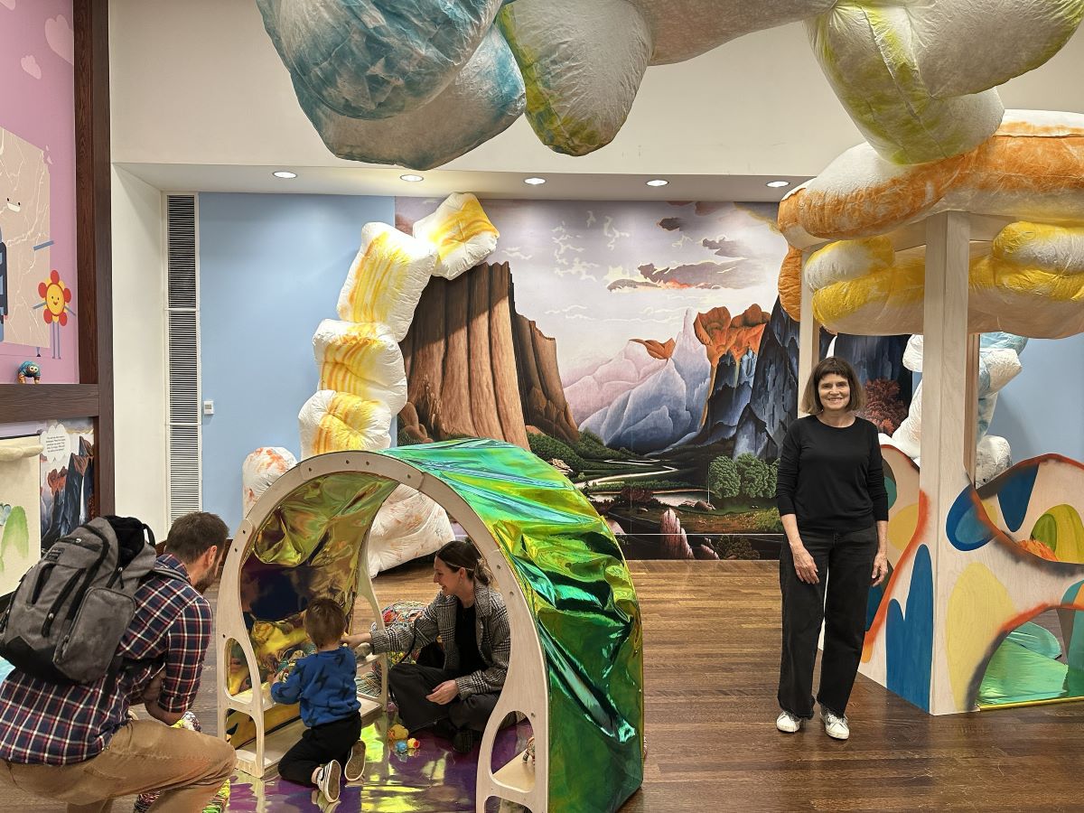 A family plays inside an art installation while a woman stands nearby.