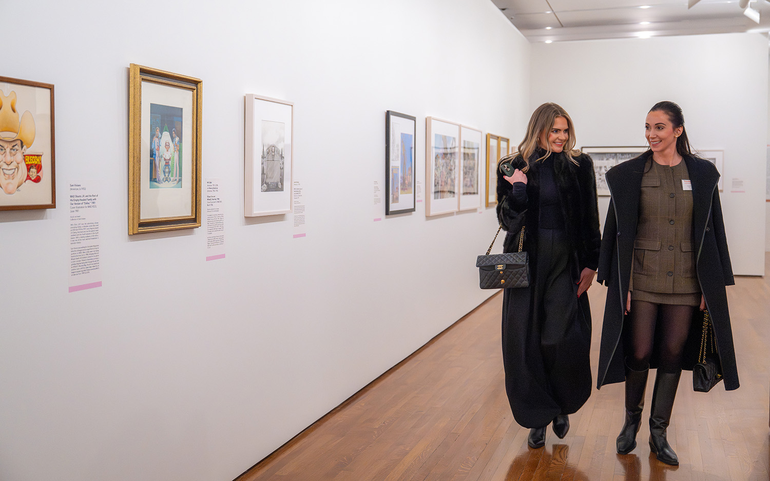 Two white women walk through a gallery
