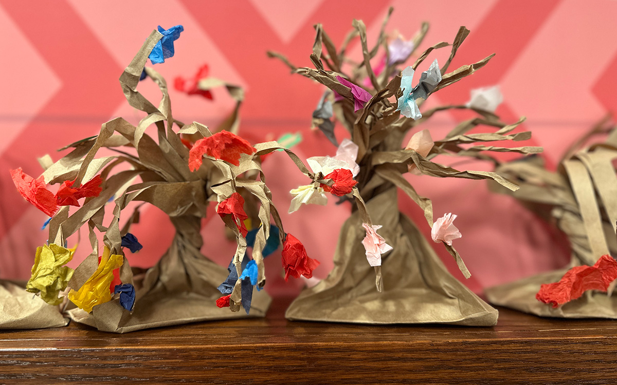 Sculptures -- made of colorful paper and representing tree-like forms -- sit on a wood shelf.