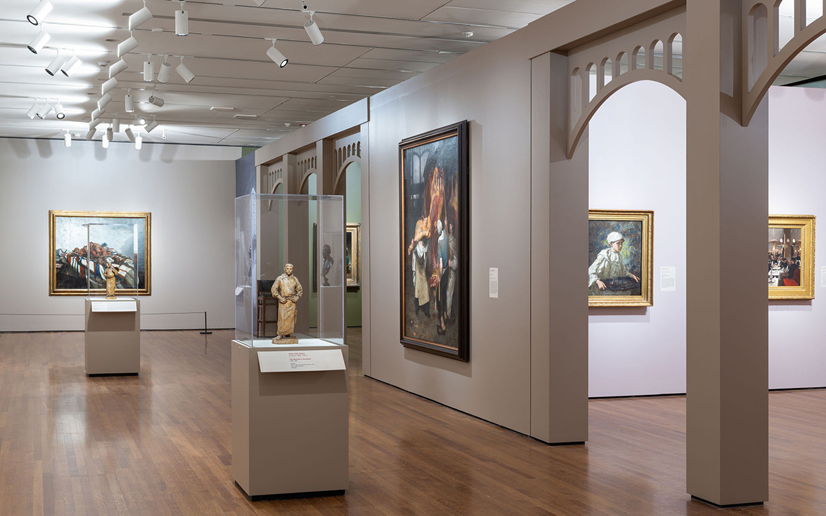 Sculptures on pedestals in a gallery with ornate arches