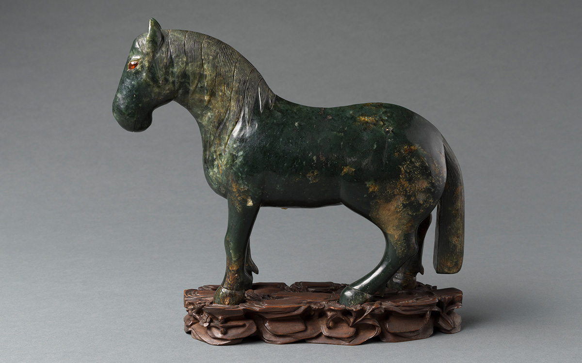 Profile of a green horse standing on a brown base