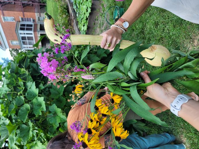 An artist paints flowers with other painters at the U-shaped table looking at a flower arrangment.