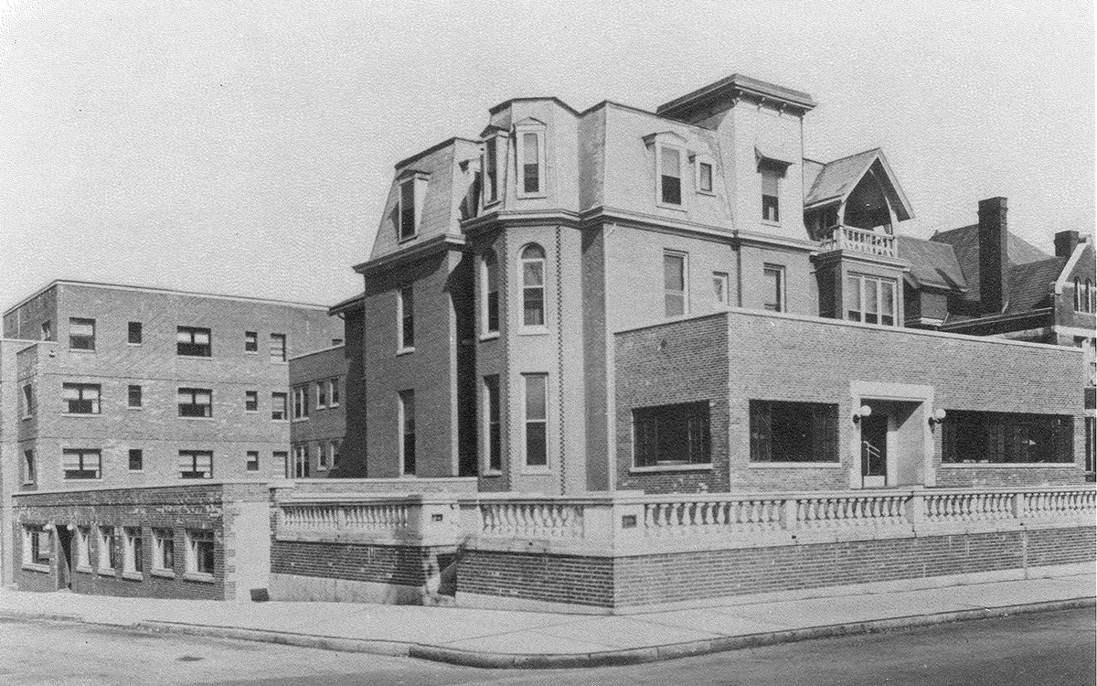 Black and white photo of a large 3-story Victorian hose with modern additions