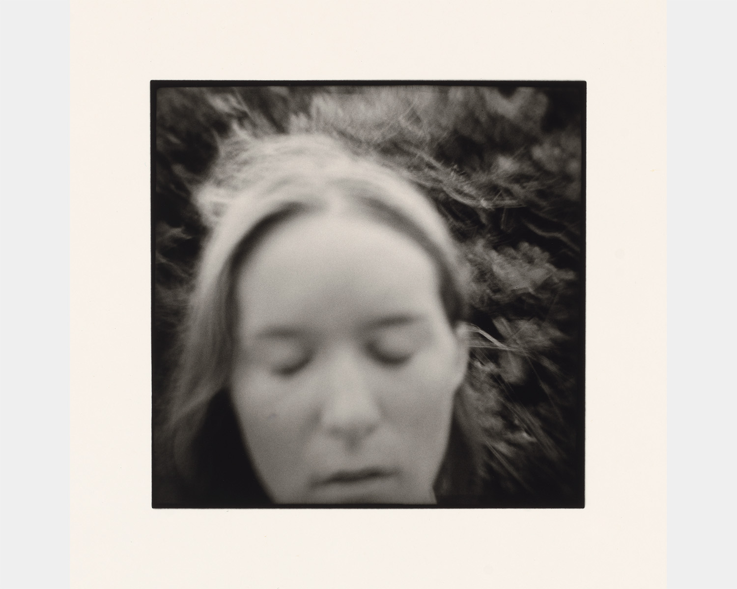 A black and white photo of a white woman with her eyes closed