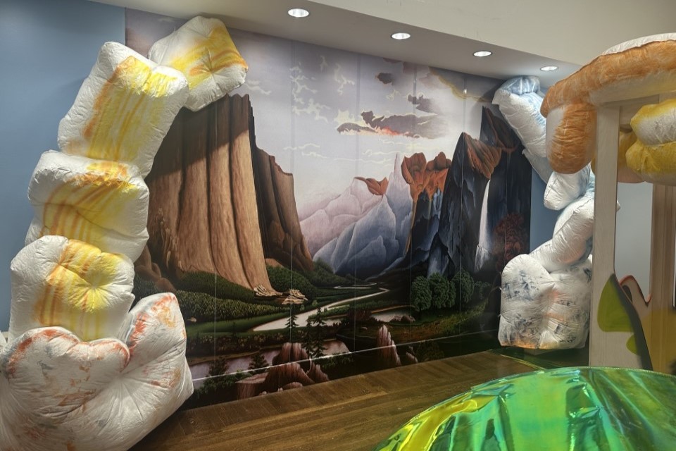 Pillow like forms surround a large mural painting depicting a landscape.