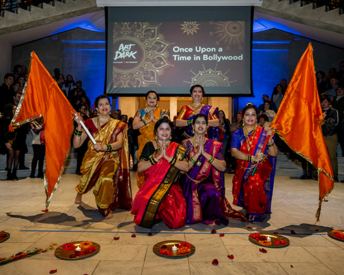 A group of dancers pose with flags and candles in the Great Hall