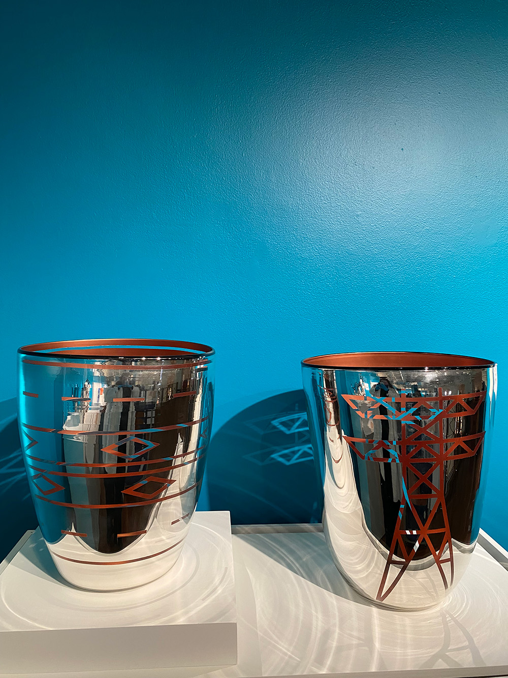 Two shiny silver cups with geometric designs