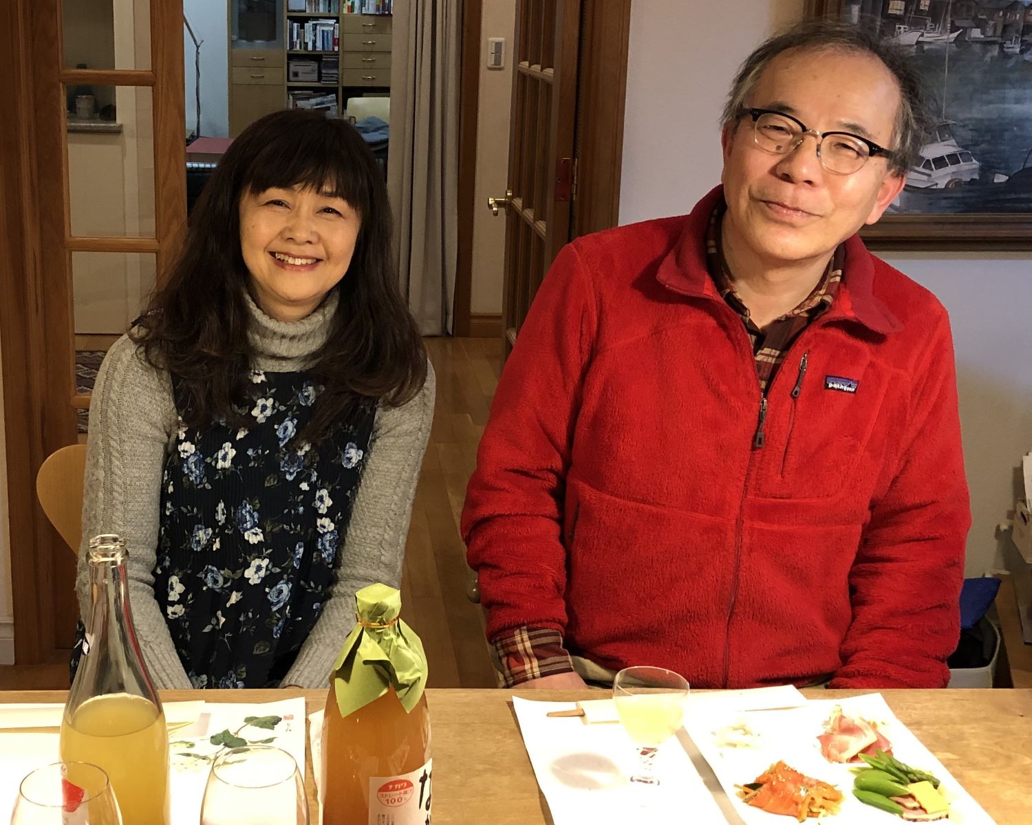 A woman (left) and a man (right) sit at a dining table with dinner plates and beverage bottles.