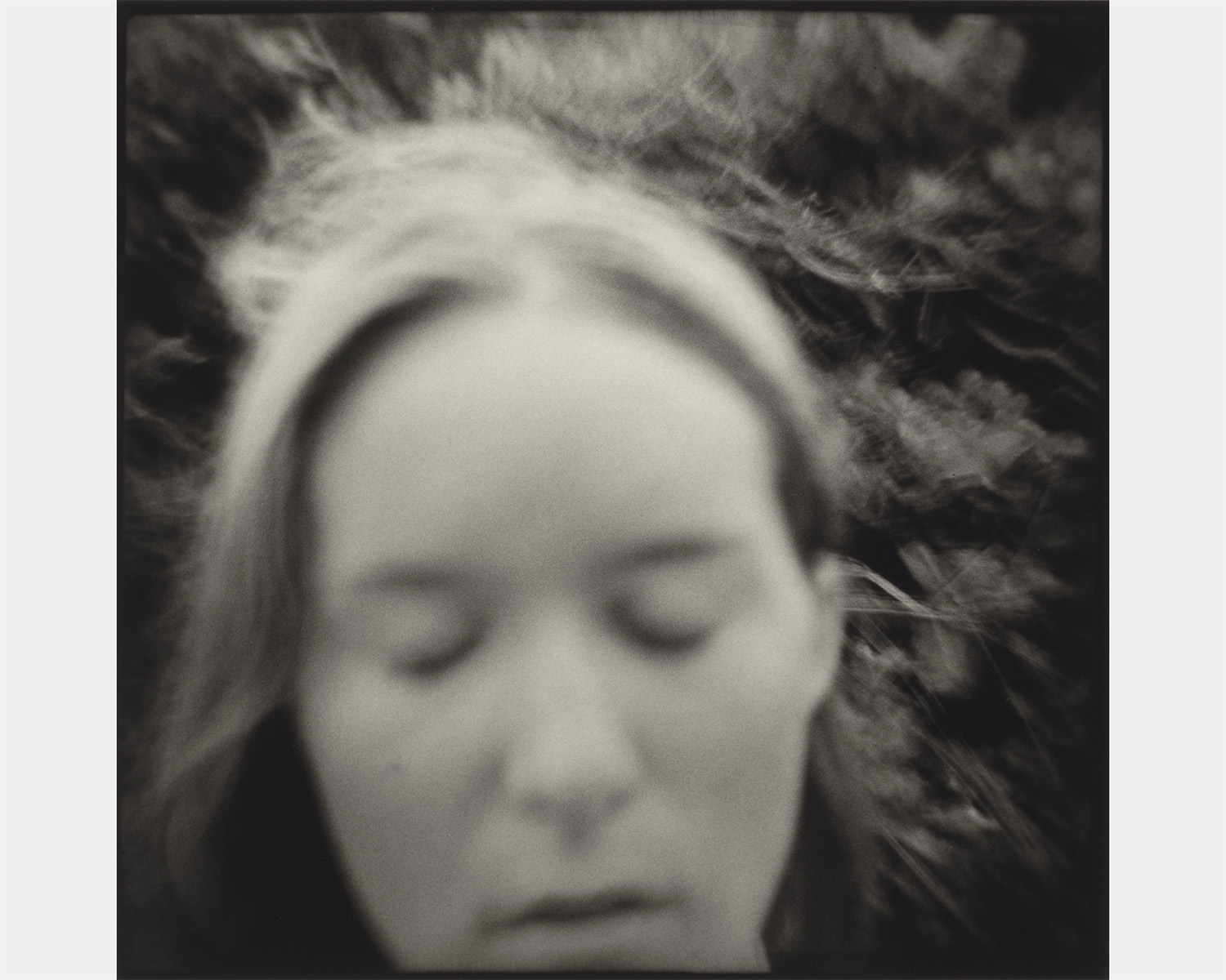 A black and white photo of a white woman with her eyes closed