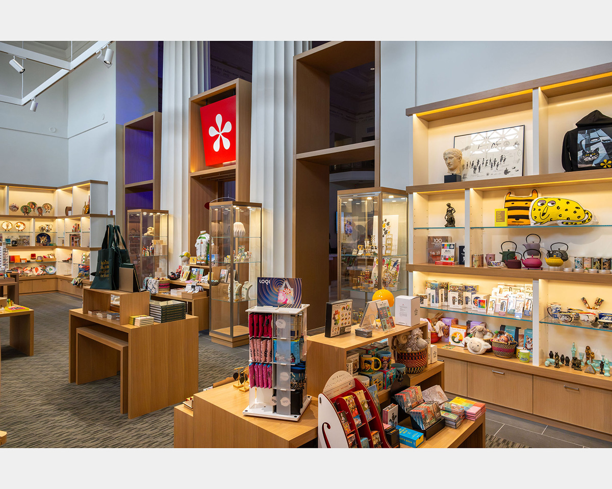 Wood shelves, cabinets, and tables displaying retail merchandise. Two large columns in the background mark the entryways into the shop.