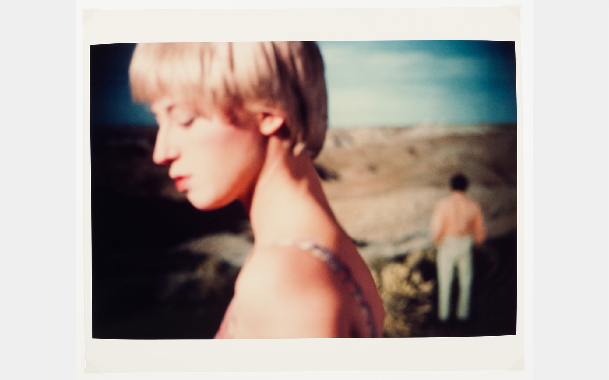 A color photo of a white woman with short blonde hair in front of a landscape