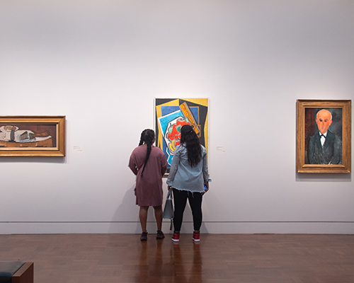 Two visitors inspect a painting