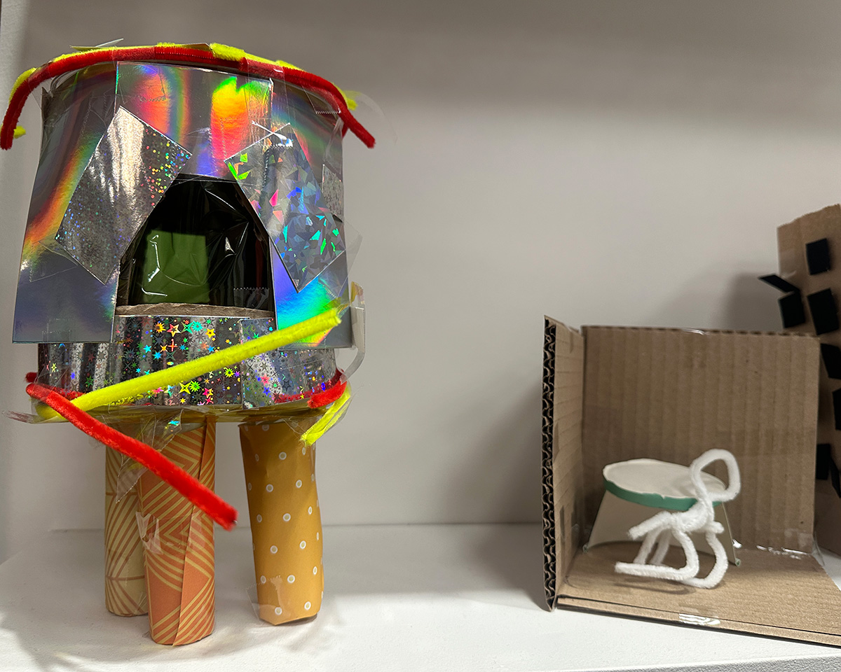 Shiny house-like structure on three stilts made of paper.