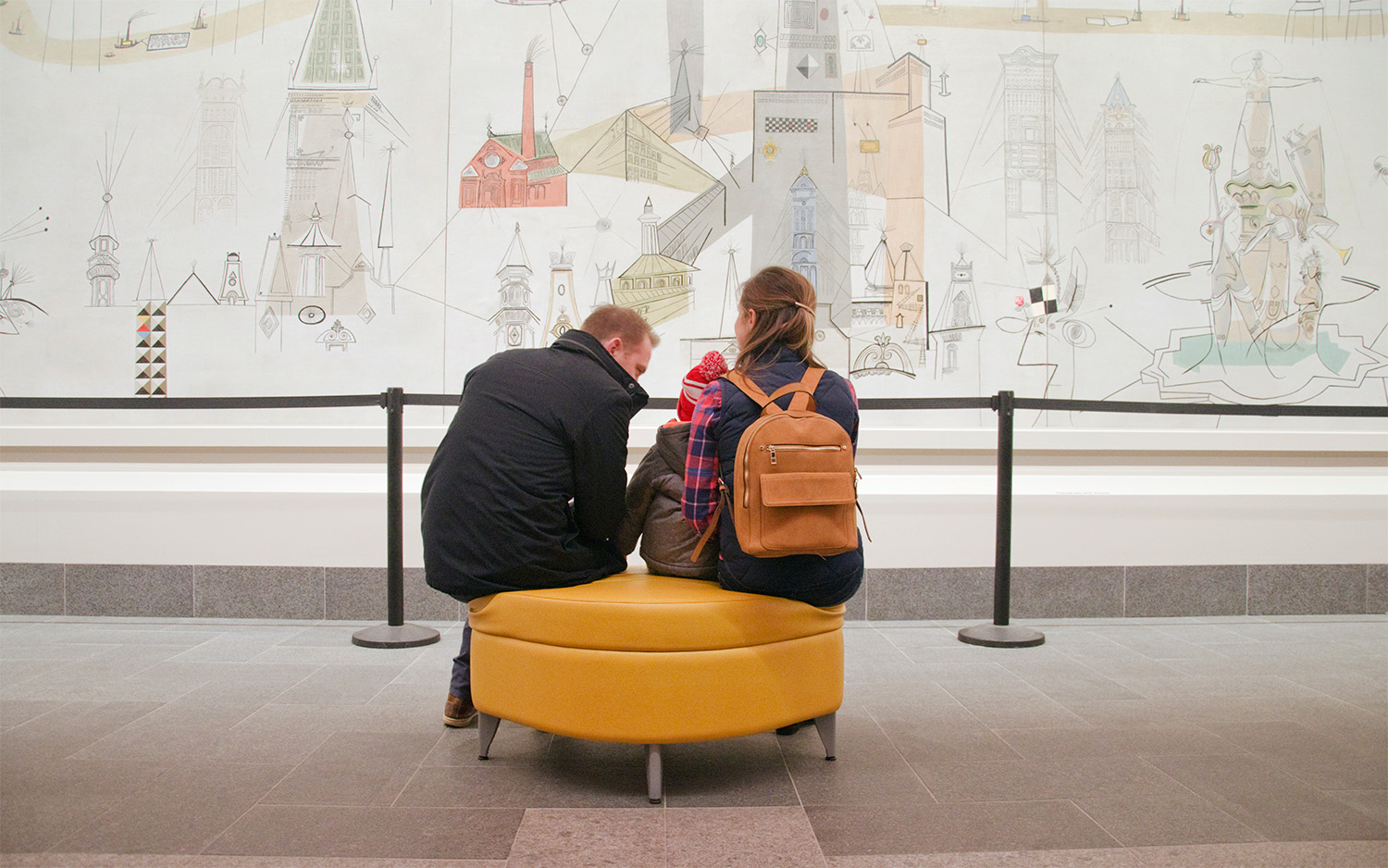 A family sits together looking at a mural