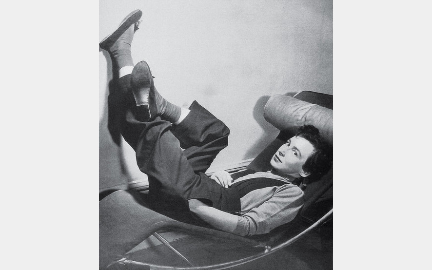 Black and white photo of a woman reclining in a curved seat