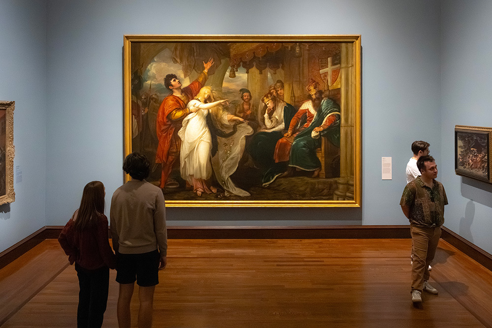 Visitors look at a massive painting