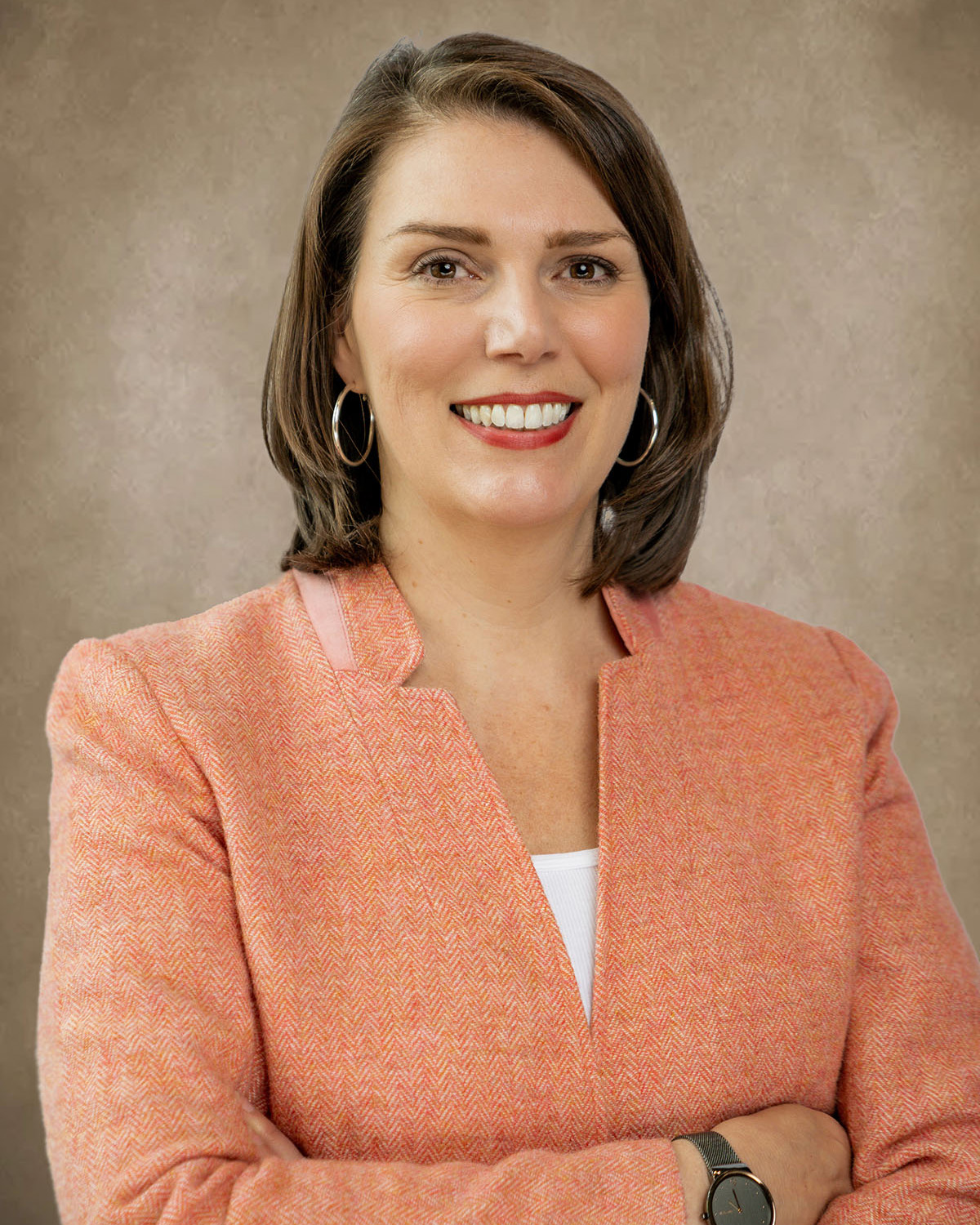 A white woman with brown hair wearing a peach blazer