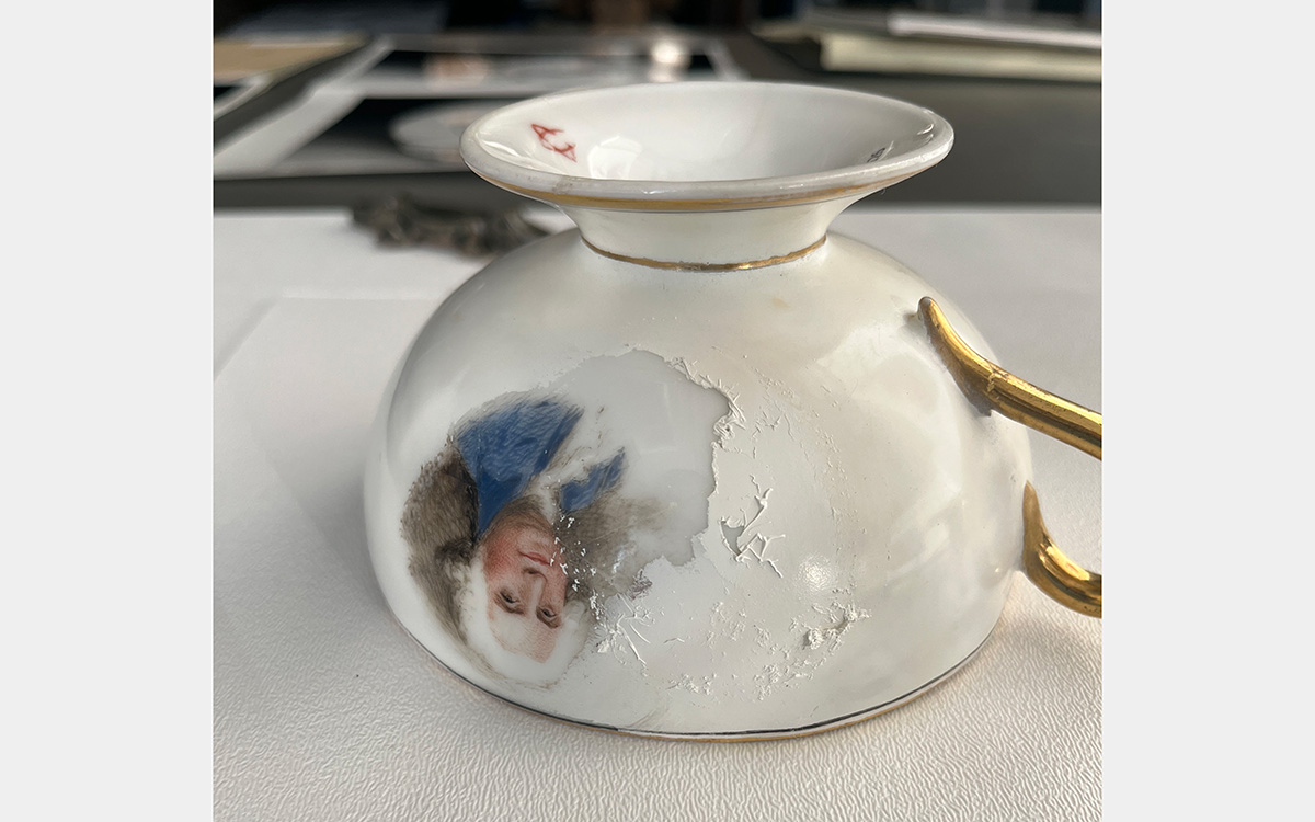 Upside down teacup with colored painting of a man in a white wig