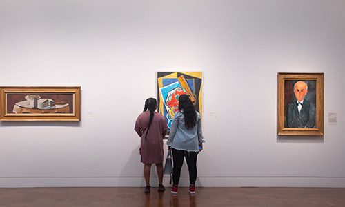 Two people look at a painting in a gallery