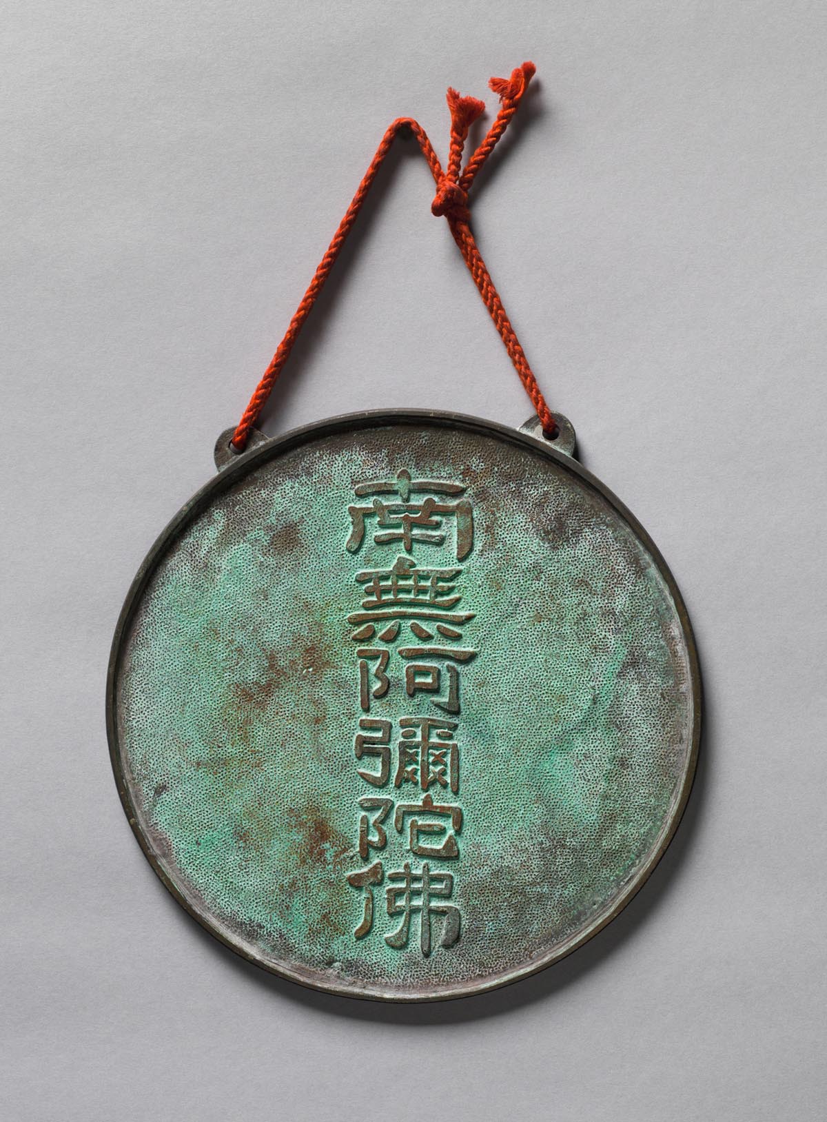 A round patinaed bronze mirror with six characters.