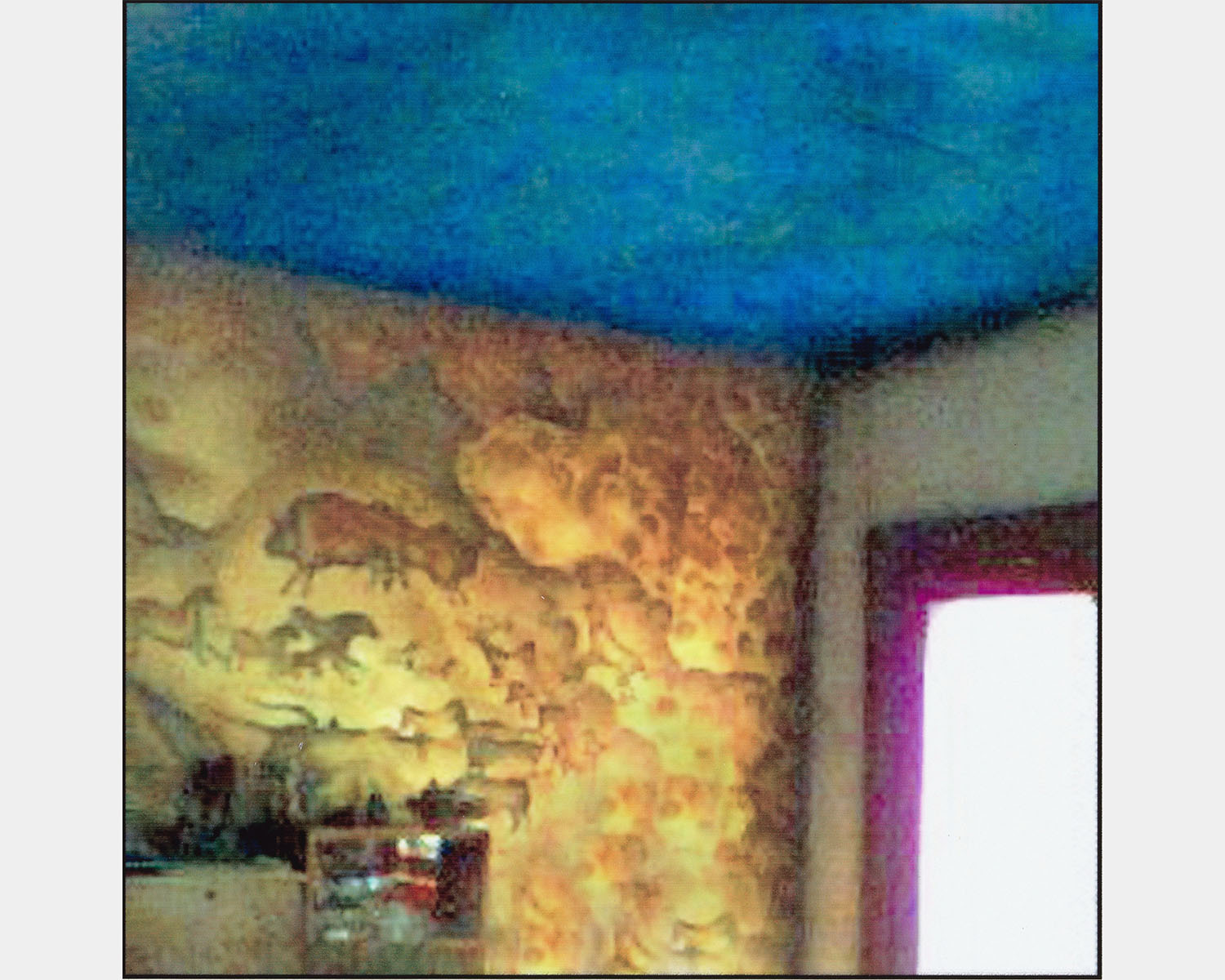 A color photo of the corner of a room with cave paintings on the wall