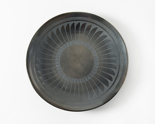 A black plate with a repeating blade shape circling around a black center