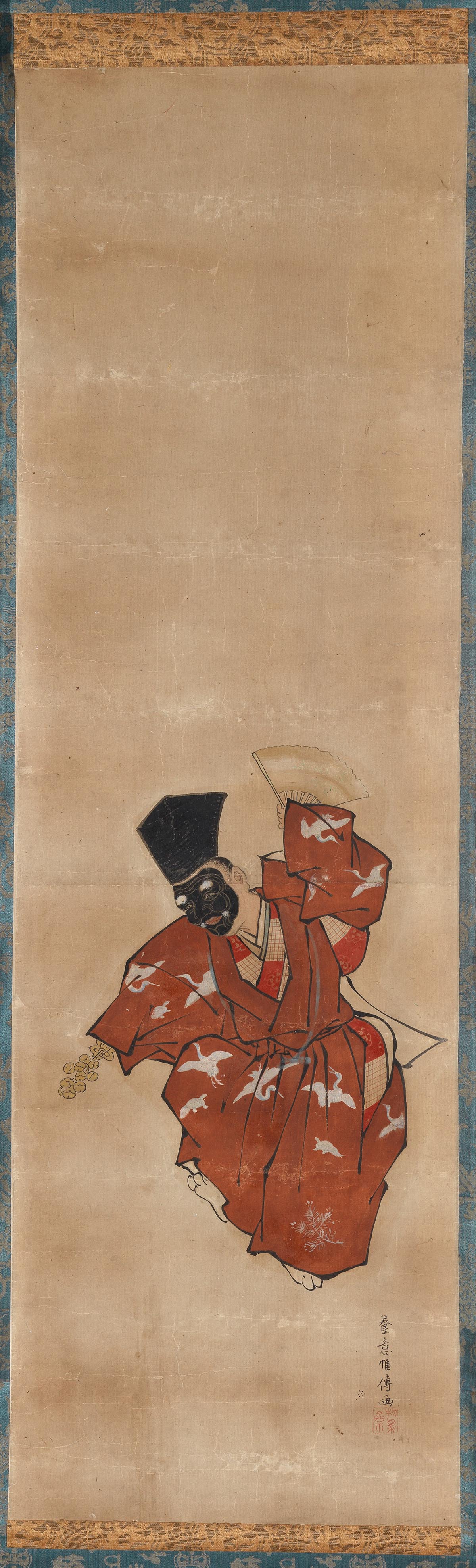 A performer wearing a black mask dances with a fan and bells.