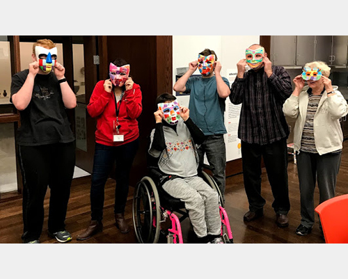 Visitors hold up masks they've made at the museum