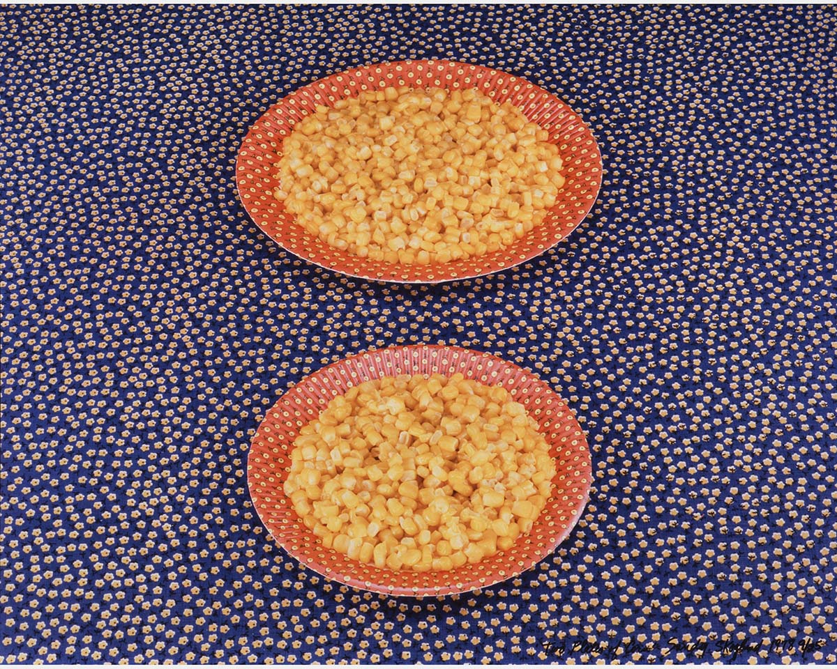 A color photo of two red plates filled with corn on a blue polka dot fabric